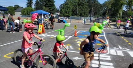 kids wearing helmets riding their bikes and scooters.