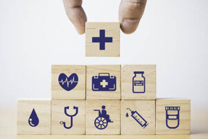 Hand putting and stacking Healthcare and medical icons which print screen on wooden cube block for health insurance concept.