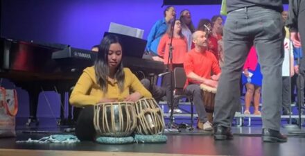Tacoma Refugee Choir members and musicians perform on stage during a concert.