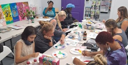 Group of people painting on canvases at an arts and crafts workshop at Mattice Beauty Supply.