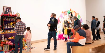 Families looking at the community-created altars for Dia de los Muertos in the Tacoma Art Museum gallery.