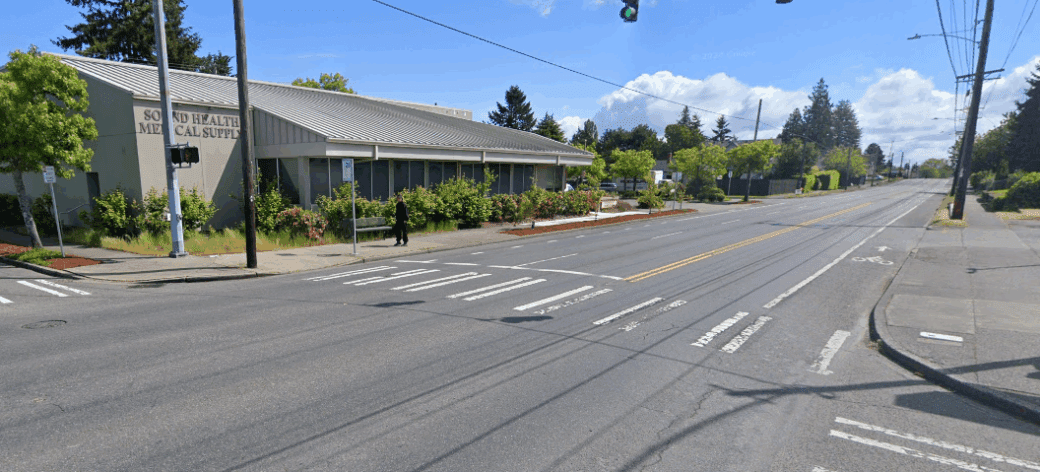 Street view of intersection at South 12th Street and Pine Street looking northeast, showing missing curb ramps and cracked pavement