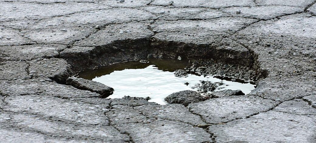 Photo of pavement deterioration including severe cracking and a pothole
