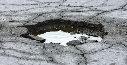 Photo of pavement deterioration including severe cracking and a pothole