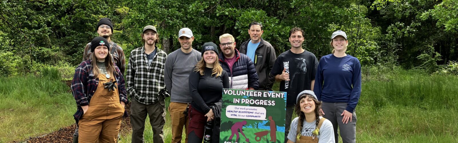 About 10 volunteers pose together for a group photo with a sign reading 