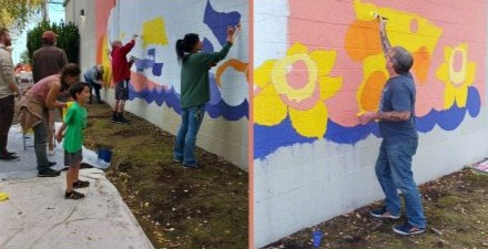 Community members help paint a mural with SENCo Creates!