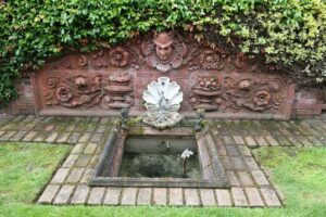 Salvaged Head of Mercury architectural ornament from former Fire Station No. 6 displayed as part of a decorative brick in garden. 