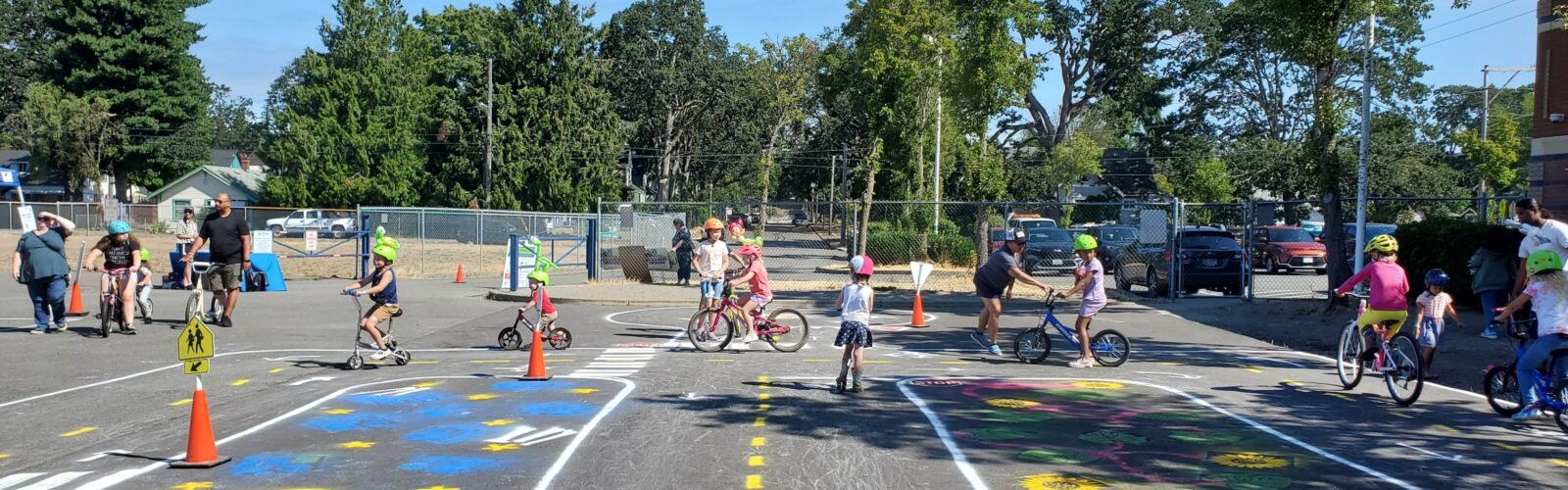 A pop-up traffic garden course painted on the blacktop at Edison Elementary. Children are riding bikes and scooters in the background.