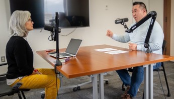Photo of Media and Communications Office Director Amy Clancy and City Manager Hyun Kim seated at a table with podcast microphones, recording an episode of the Talk Tacoma podcast.